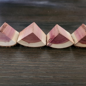 May include: Four triangular pieces of wood, each with a curved edge, are arranged in a row. The wood is a reddish-brown color with a natural grain pattern.