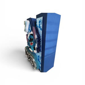 May include: A blue, layered paper art piece featuring the character Stitch from Lilo & Stitch. The design includes the name "Noah" and the number "1". The background has a floral pattern.