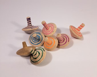 May include: A collection of eight wooden spinning tops with colorful painted designs. The tops are made of natural wood and have a variety of colors and patterns.