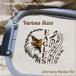 May include: An embroidered design featuring an eagle's head, musical notes, and the text "EAGLES BAND" in brown thread. The words "Various Sizes" and "Embroidery Machine File" are also present. The design is set in an embroidery hoop.