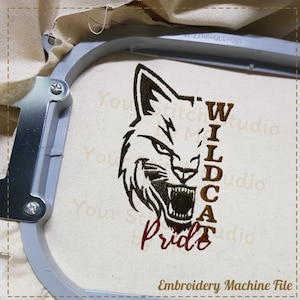 May include: Embroidered design of a wildcat head with the words "Wildcat Pride" in brown and red thread. The design is on a white fabric and is likely for a machine embroidery project.