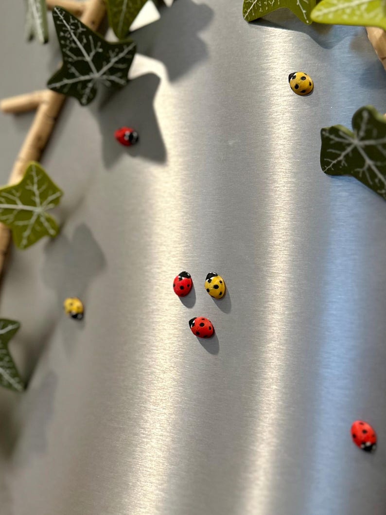 May include: A silver surface with a variety of red and yellow ladybug magnets. The ladybugs are arranged in a random pattern.