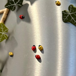 May include: A silver background with a variety of red and yellow ladybugs. The ladybugs are arranged in a random pattern.