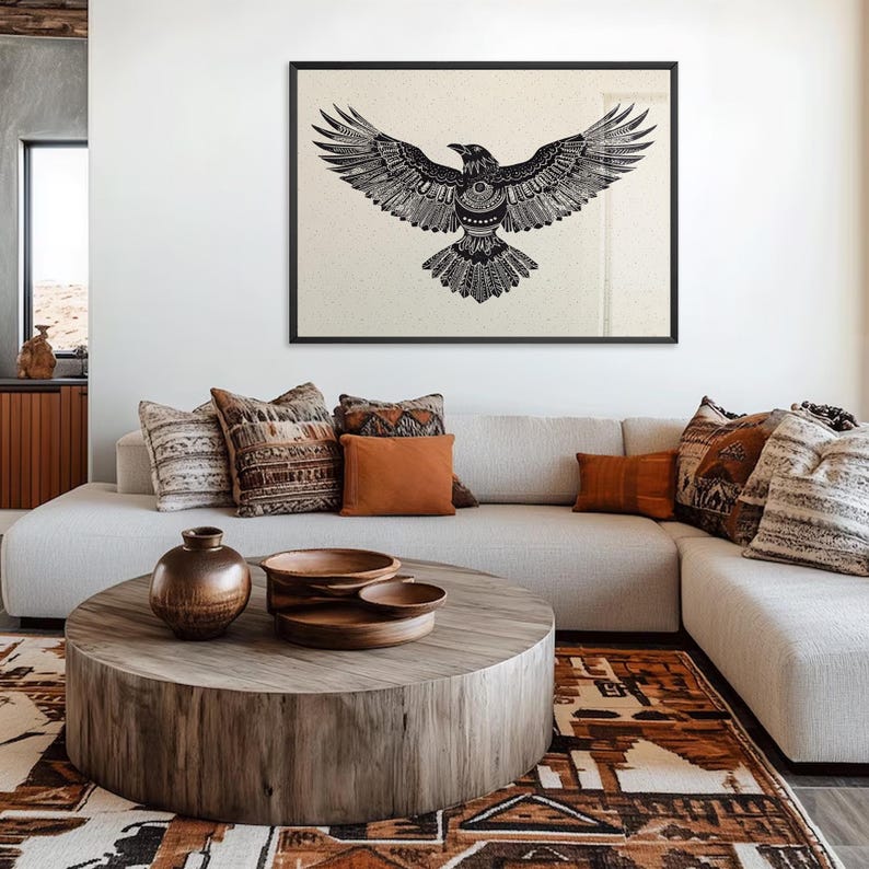 K&ouml;nnte beinhalten: Ein gerahmter Schwarz-Wei&szlig;-Kunstdruck eines Raben mit ausgebreiteten Fl&uuml;geln h&auml;ngt &uuml;ber einem hellfarbigen Ecksofa. Das Wohnzimmer verf&uuml;gt &uuml;ber einen Holztisch, dekorative Kissen und einen gemusterten Teppich, was eine gem&uuml;tliche, b&ouml;hmische &Auml;sthetik schafft.