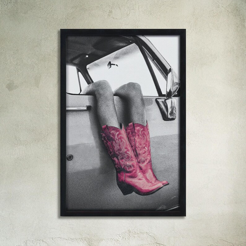 May include: A black and white photograph of a person's legs wearing pink cowboy boots sticking out of a car window.