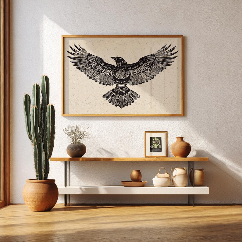 K&ouml;nnte beinhalten: Gerahmte Schwarz-Wei&szlig;-Illustration eines Raben mit ausgebreiteten Fl&uuml;geln h&auml;ngt &uuml;ber einem Regal mit dekorativen Gegenst&auml;nden. Ein hoher Kaktus in einem Terrakottatopf und andere T&ouml;pferwaren erg&auml;nzen die Einrichtung.