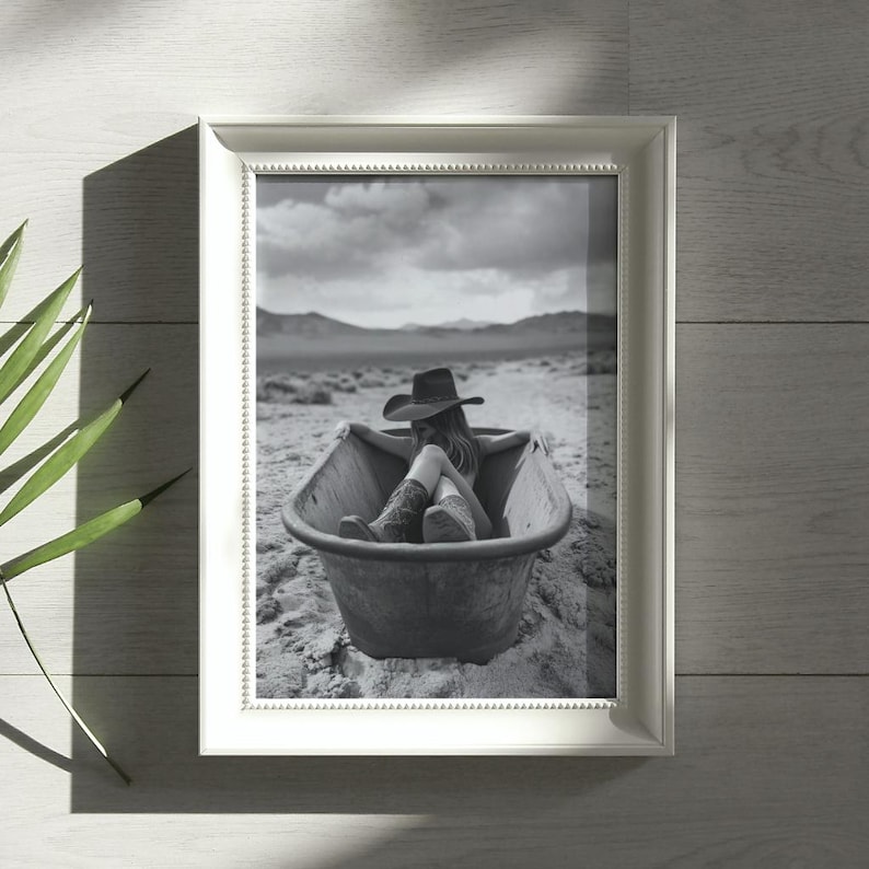 K&ouml;nnte beinhalten: Ein Schwarzwei&szlig;foto einer Person, die einen Cowboyhut und Stiefel tr&auml;gt und in einer Badewanne in der W&uuml;ste sitzt.