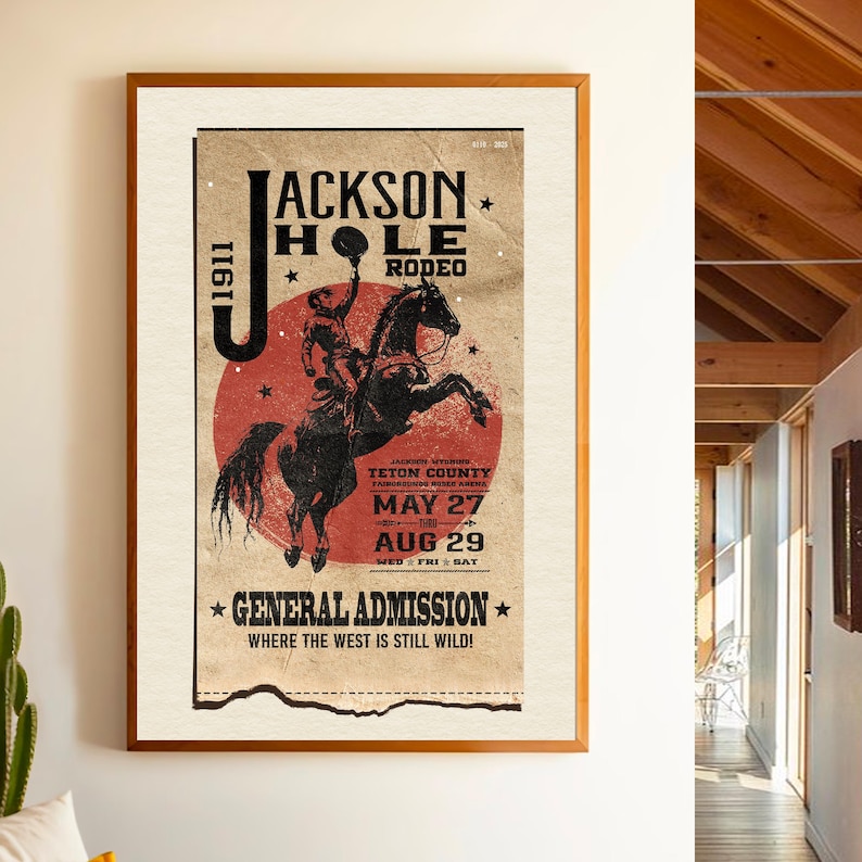 May include: Vintage poster advertising the Jackson Hole Rodeo in Teton County, Wyoming. The poster features a cowboy riding a bucking horse with a red, white, and blue color scheme. The dates of the rodeo are May 27th through August 29th. The text reads "Jackson Hole Rodeo, Teton County, Wyoming, May 27th - Aug 29th, General Admission, Where the West is Still Wild!"
