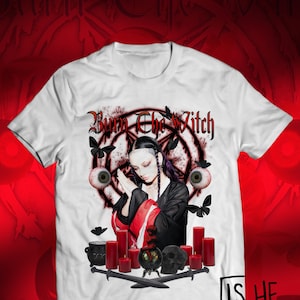 Puede incluir: Camiseta blanca con un diseño gráfico que presenta el texto "Burn the Witch" sobre una ilustración de una persona, ojos, mariposas, velas y una calavera. También está presente la frase "Is he the boy from the video?".