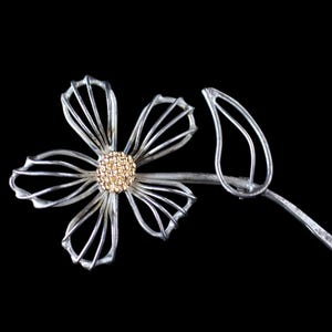May include: A silver wire flower brooch with a gold centre. The flower has five petals and a leaf stem.