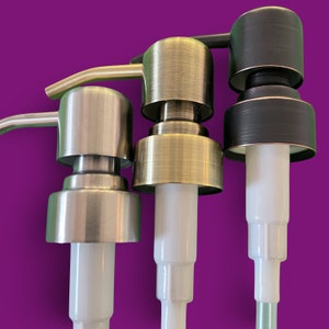Puede incluir: Tres tapas de bomba de jab&oacute;n diferentes en acabados dorado, plateado y negro. Las bombas son de metal y tienen un tubo de pl&aacute;stico blanco.