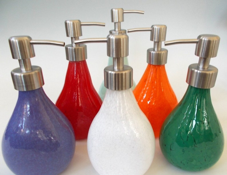Puede incluir: Seis dispensadores de jab&oacute;n de vidrio con bombas de acero inoxidable. Los dispensadores son de varios colores: morado, rojo, verde, blanco, naranja y verde claro.