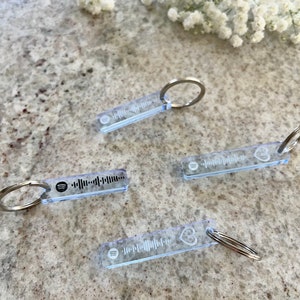 May include: Four clear acrylic keychains with a silver metal ring. Each keychain has a black and white Spotify barcode printed on it. One keychain has a small heart shape etched into the acrylic.