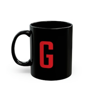 Peut inclure: Une tasse en céramique noire avec une lettre "G" rouge imprimée sur le devant.