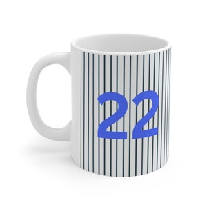 Peut inclure: Une tasse en céramique blanche avec un motif rayé noir et blanc et le numéro 22 en bleu.