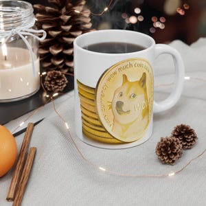 Peut inclure: Une tasse en céramique blanche avec un motif de pièce d'or représentant un chien Shiba Inu avec le texte "very currency wow much coin how much wow" imprimé sur la pièce.