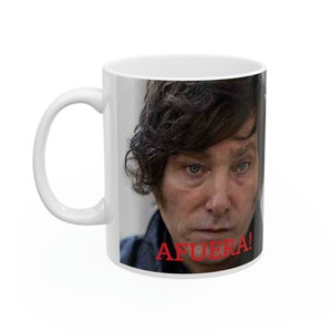 Könnte beinhalten: Weiße Keramiktasse mit einem Foto eines Mannes mit dunklen Haaren und einem ernsten Ausdruck. Der Text "AFUERA!" ist in Rot am Boden der Tasse aufgedruckt.
