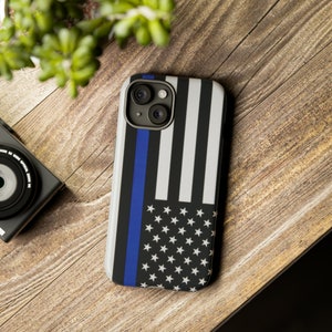 May include: A black and white American flag phone case with a blue line running down the left side. The case has a cutout for the camera lens.