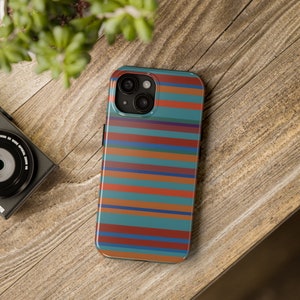 May include: A phone case with a striped pattern in shades of blue, orange, red, and brown. The case has a cutout for the camera lens.