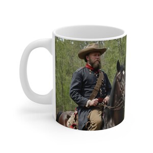 Peut inclure: Un homme en uniforme bleu et un chapeau marron chevauche un cheval noir dans une zone boisée. Il a une barbe et tient les rênes.