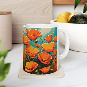 Könnte beinhalten: Weiße Keramiktasse mit einer farbenfrohen Illustration von orangefarbenen Mohnblumen vor blauem Himmel. Die Tasse hat einen weißen Henkel.