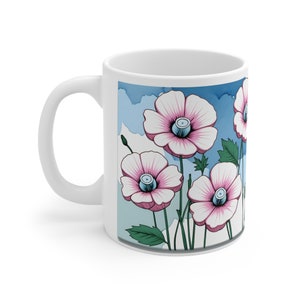 Könnte beinhalten: Weiße Keramiktasse mit einem Design aus rosa Blüten mit blauen Zentren vor einem blauen und weißen Aquarellhintergrund.