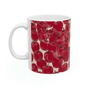 Peut inclure: Une tasse en céramique blanche avec un motif de pommes rouges. Les pommes sont dessinées dans un style vintage et sont dispersées sur la tasse.