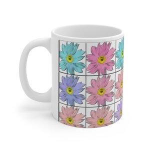 Könnte beinhalten: Weiße Keramiktasse mit einem Design aus neun pastellfarbenen Blumen in einem Rastermuster. Die Blumen sind blau, rosa und lila.