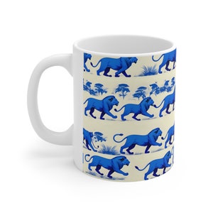 Puede incluir: Taza de cerámica blanca con un patrón azul y blanco de leones caminando por un paisaje de sabana. Los leones están estilizados y tienen un contorno azul.