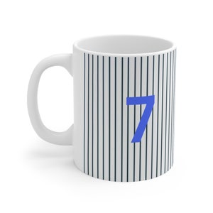 Peut inclure: Une tasse en céramique blanche avec un motif rayé noir et blanc et un numéro 7 bleu sur le devant.
