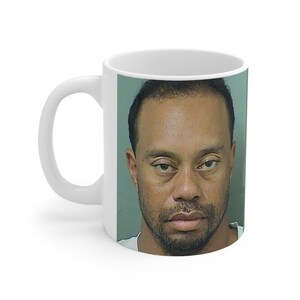 May include: White ceramic mug with a photo of a man with short black hair and a serious expression. The man is wearing a white shirt.