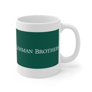 May include: White ceramic coffee mug with a green band featuring the text "LEHMAN BROTHERS" in white.