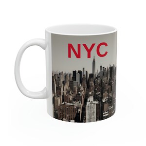 Op de afbeelding: Witte keramische mok met een stadsbeeld van New York City en de tekst "NYC" in rood.