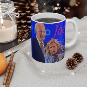 May include: White ceramic coffee mug with a blue background and a photo of Joe Biden and Kamala Harris. The text "It's So Joe" is printed on the mug.