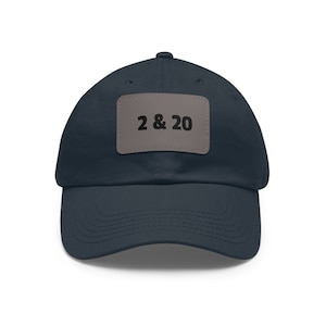 以下が含まれることがあります： 黒文字で「2 & 20」と書かれたグレーのパッチが付いたネイビーブルーのベースボールキャップです。
