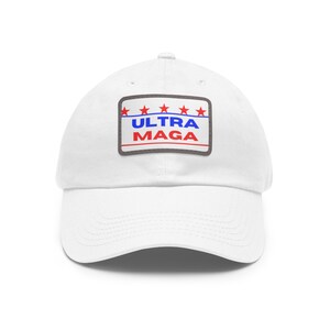 May include: White baseball cap with a curved brim. The cap features a rectangular patch with the text "ULTRA MAGA" in red and blue, with red stars and blue lines above the text. The patch is outlined in a gray border.