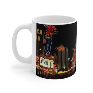 Peut inclure: Mug en céramique blanche avec une image de fond noire d'une enseigne au néon avec une silhouette de cow-boy et les mots "Golden Nugget" et "Paris Jr."