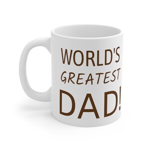 Könnte beinhalten: Weiße Keramik-Kaffeetasse mit einer braunen Aufschrift, die "WORLD'S GREATEST DAD!" lautet.
