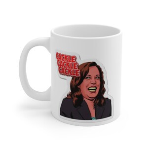 Könnte beinhalten: Weiße Keramik-Kaffeetasse mit einer bunten Illustration einer Frau mit den Worten "GACKLE GACKLE GACKLE" in Rot.