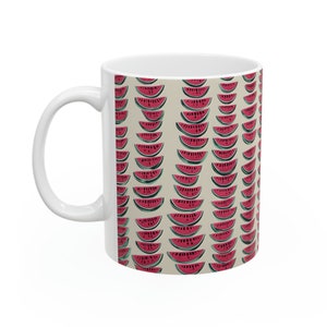 Può includere: Tazza in ceramica bianca con un motivo di fette di anguria rosa su uno sfondo beige.