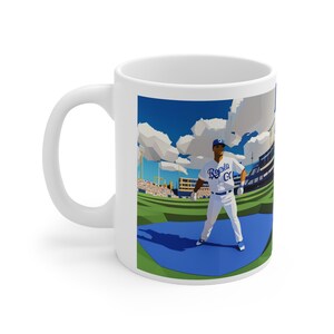 Könnte beinhalten: Eine weiße Keramiktasse mit einer Grafik eines Baseballspielers in einer blau-weißen Uniform mit dem Text "Royals" auf der Vorderseite. Der Spieler steht auf einem Baseballfeld mit blauem Himmel und weißen Wolken im Hintergrund.