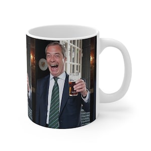 Op de afbeelding: Witte keramische mok met een foto van een man in pak die lacht en een glas bier vasthoudt. De man staat voor een pubdeur.