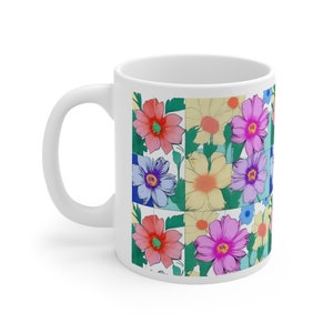 Könnte beinhalten: Weiße Keramiktasse mit einem Blumenmuster. Das Muster zeigt rosa, gelbe, blaue und grüne Blumen auf weißem Hintergrund.