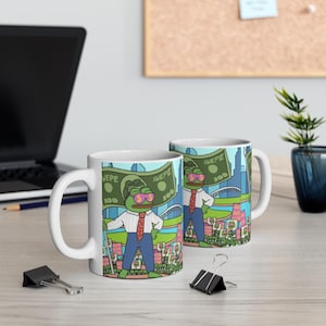 May include: Two white ceramic mugs with a green frog character wearing sunglasses and a red tie. The frog is standing in front of a large dollar bill with the text "SWEPE" and "100" printed on it. The mugs are on a wooden table.
