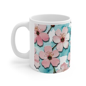 Peut inclure: Une tasse en céramique blanche avec un motif de fleurs de cerisier roses sur un fond aquarelle bleu.