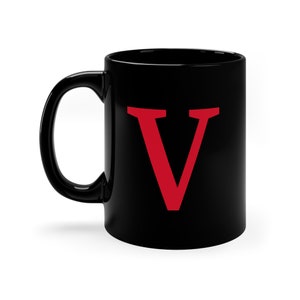 Peut inclure: Une tasse en céramique noire avec une lettre V rouge sur le devant.