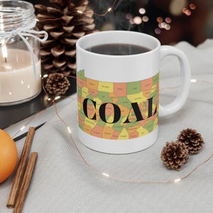 Może przedstawiać: Biały kubek ceramiczny z mapą Pensylwanii i napisem "COAL" czarnymi literami. Kubek jest wypełniony kawą, a z jego górnej części unosi się para.