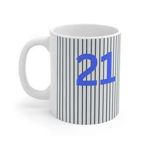 Könnte beinhalten: Weiße Keramiktasse mit einem schwarz-weißen Streifenmuster und der Zahl 21 in Blau.