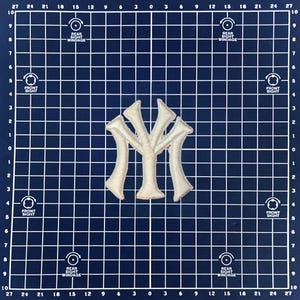 May include: An embroidered patch featuring the interlocking "NY" logo of the New York Yankees baseball team. The patch is off-white with a textured appearance, set against a dark blue grid background. Ideal for apparel or craft projects.