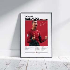Pode incluir: Pôster emoldurado com Cristiano Ronaldo com a camisa vermelha da seleção portuguesa. O pôster inclui seu nome, assinatura e destaques da carreira em um fundo vermelho. A imagem está em uma moldura preta.